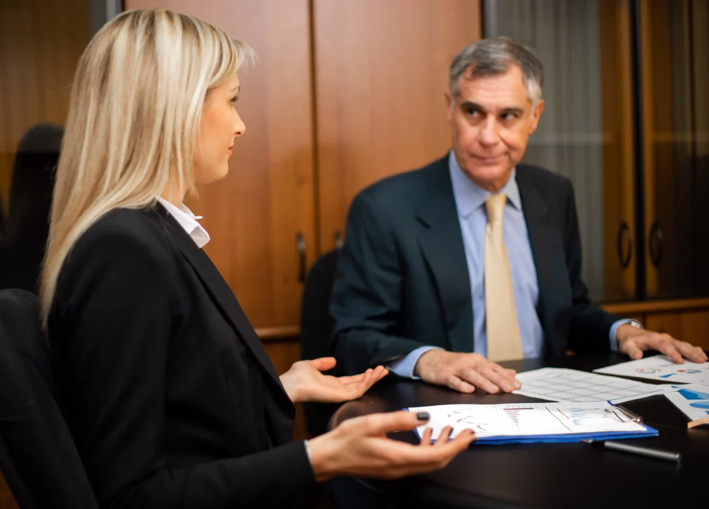 A professional discussion in a modern office between a female and male colleague reviewing charts and documents on employment tribunals, exploring the question do employment tribunals favour employers in UK workplace disputes.