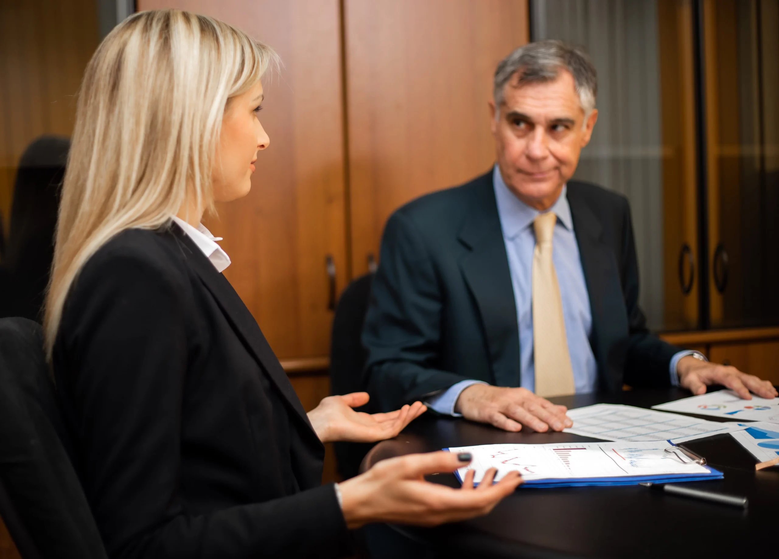 A professional discussion in a modern office between a female and male colleague reviewing charts and documents on employment tribunals, exploring the question do employment tribunals favour employers in UK workplace disputes.