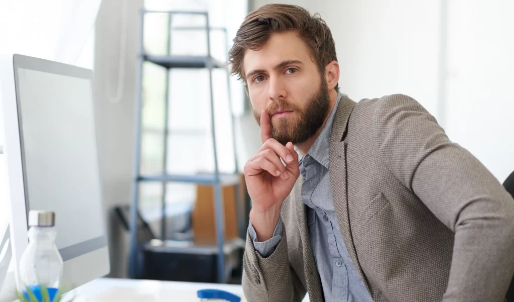 a man thinking with his hand on his beard pondering what action to take against gross misconduct at work