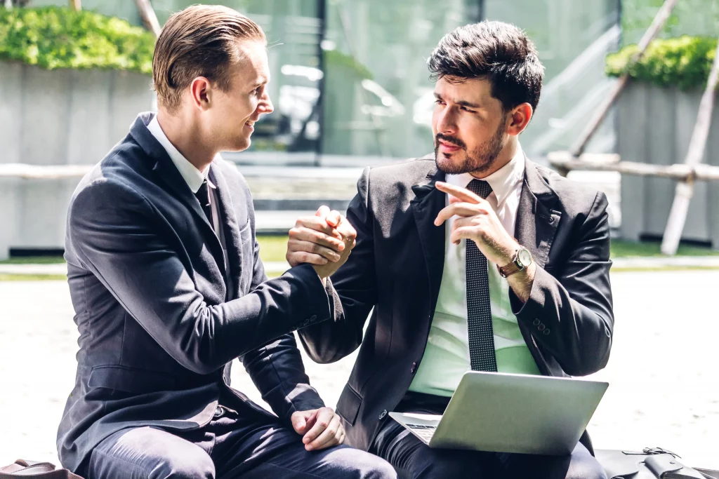 a manager outside supporting his employee while holding the laptop on his lap