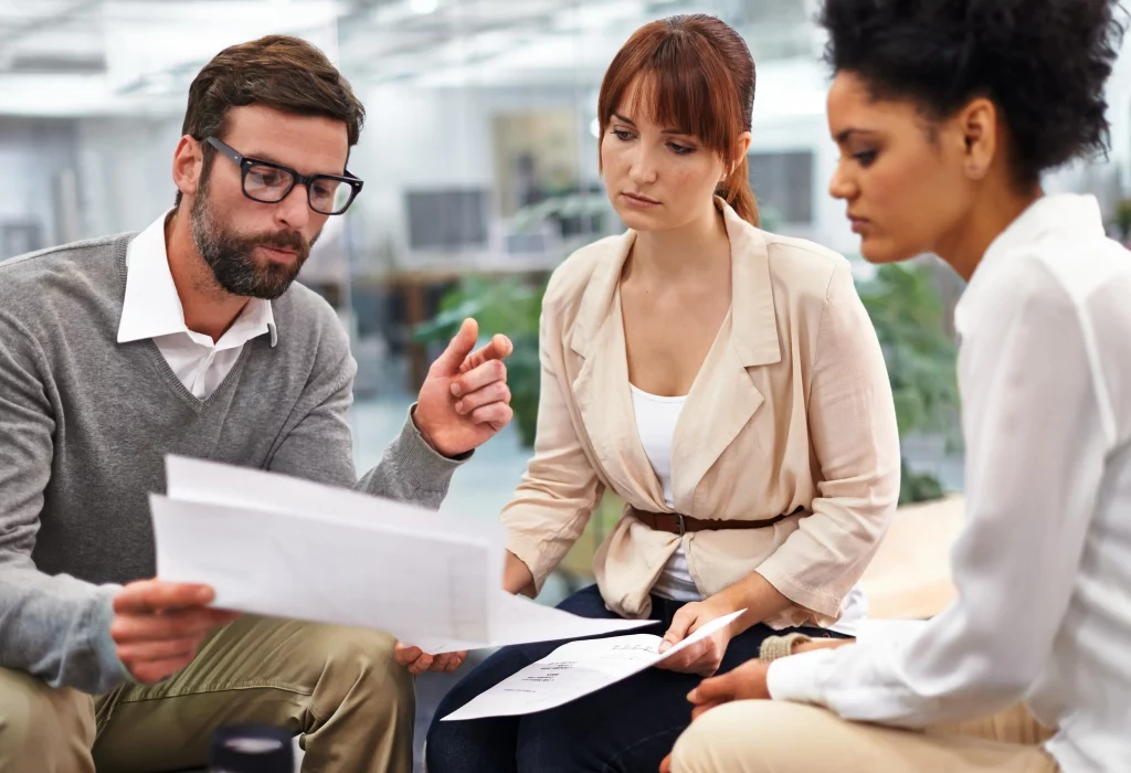 Business professionals in a modern office meeting, reviewing documents and discussing what to ask SEO consultants to optimize their B2B strategy.