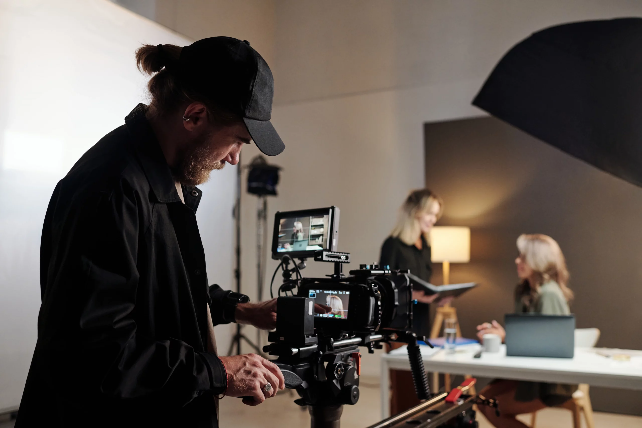 A dynamic behind-the-scenes view of a professional video production team at work, with a videographer adjusting a high-end camera on a tripod while collaborators review footage on a tablet—perfectly capturing when to employ a video production agency for polished B2B results.
