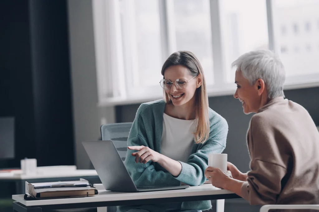an seo expert working on a laptop showing a business owner exactly how to appear on google search