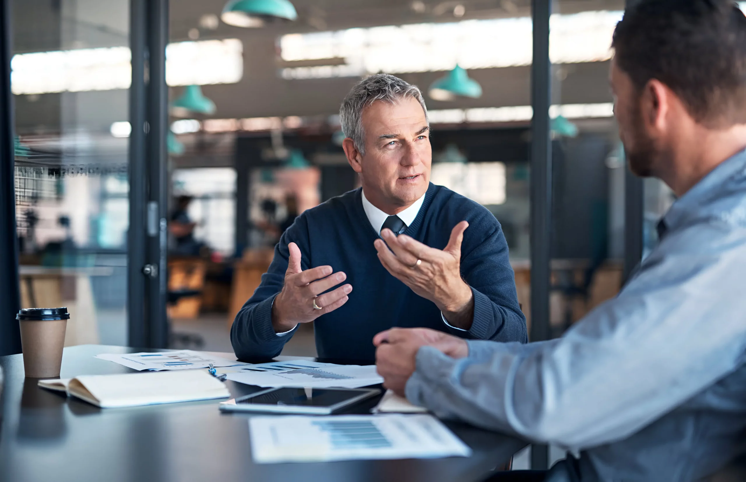 two business people sat at a desk in an office discussing what are open and closed questions
