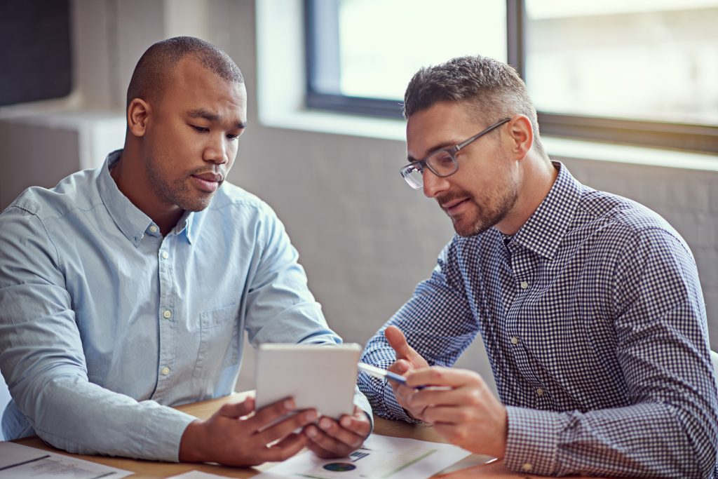 two men at a table reviewing a training course on how to dismiss an employee for poor performance