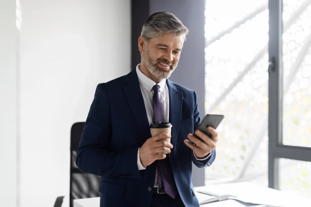 Business owner smiling while checking phone to contact an SEO firm for expert SEO services and growth support