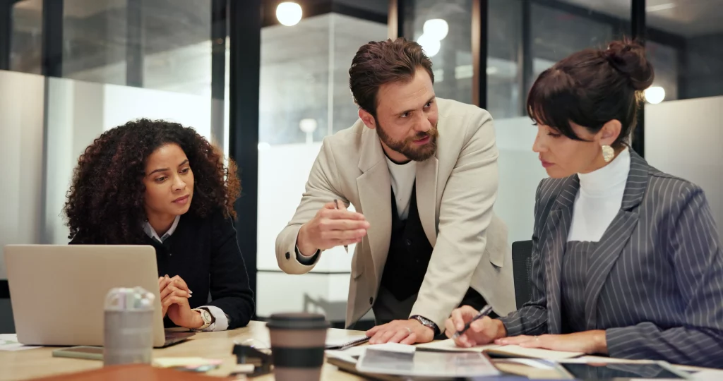 Diverse SEO agency experts in a strategy meeting, reviewing documents and brainstorming ideas