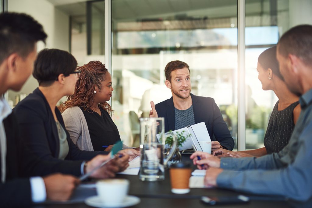 a team at a table discussing the best way to implement a company handbook