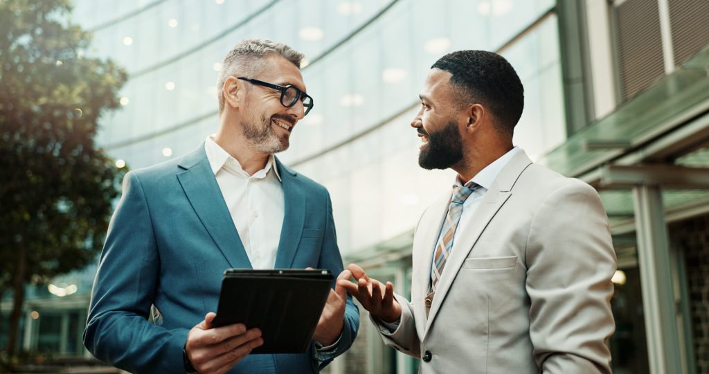 two company owners outside smiling talking about employee handbooks