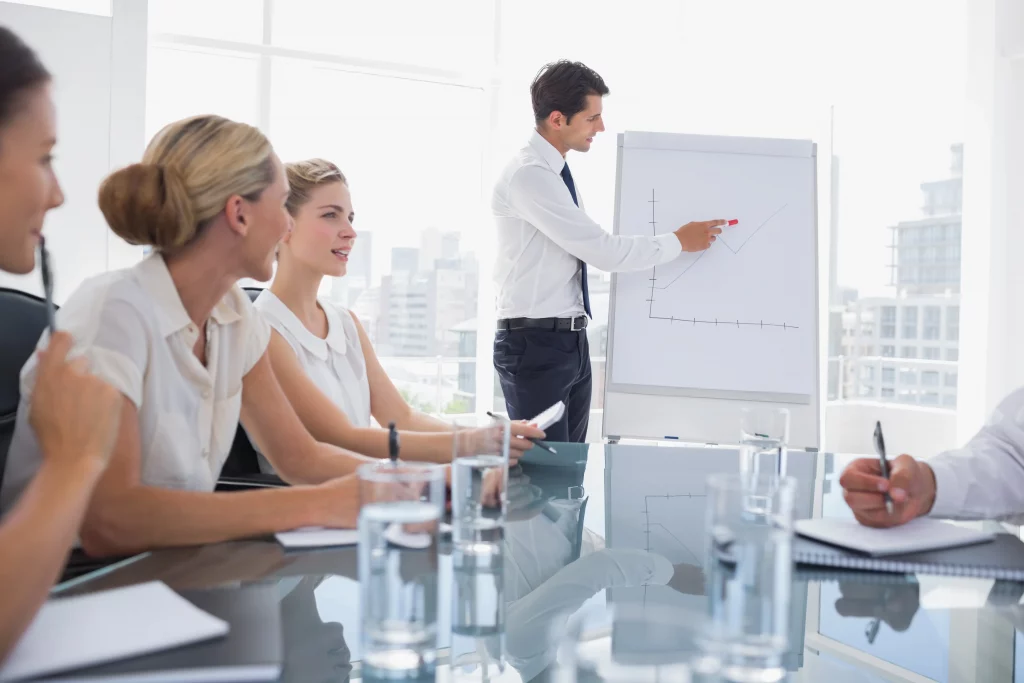 a business analyst showing collagues on a whiteboard the results of their employee retention rate