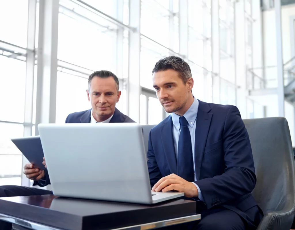 a business director showing his colleague the retention rate results on a laptop after learning how to calculate employee retention rate